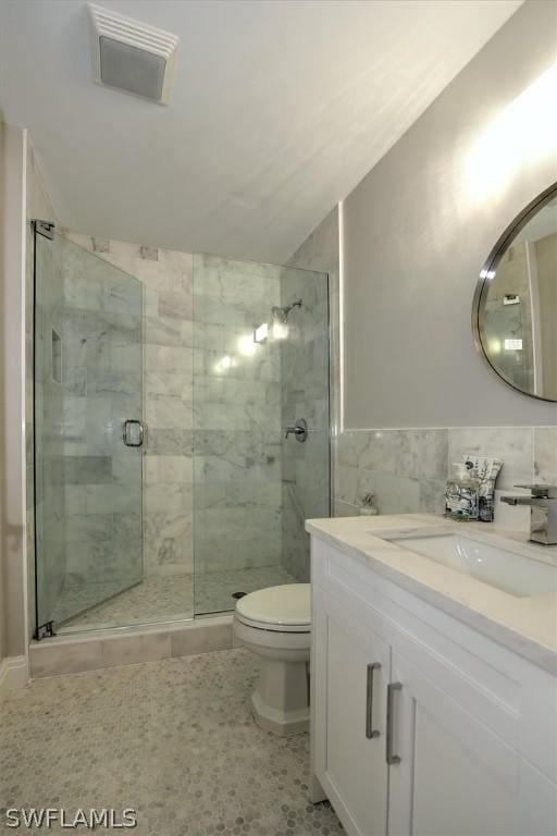 bathroom featuring tile patterned flooring, vanity, toilet, and an enclosed shower