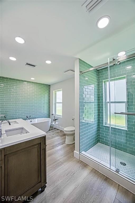 full bathroom featuring hardwood / wood-style floors, vanity, a healthy amount of sunlight, and independent shower and bath