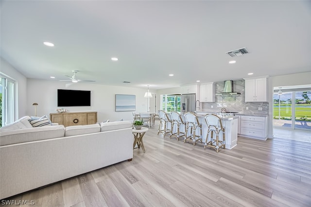 living room featuring light hardwood / wood-style flooring, ceiling fan, a healthy amount of sunlight, and sink