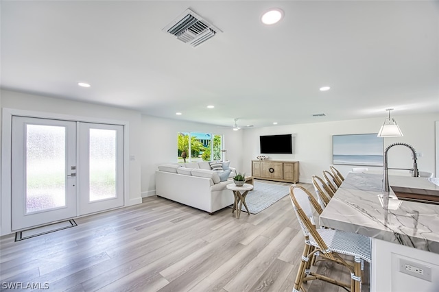 living room with french doors, light hardwood / wood-style floors, and plenty of natural light