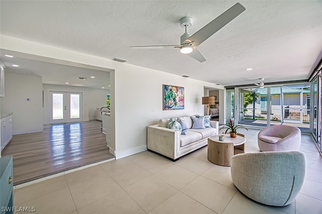 tiled living room featuring floor to ceiling windows, ceiling fan, french doors, and a textured ceiling