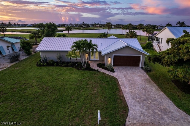 view of front of house with a yard, a water view, and a garage