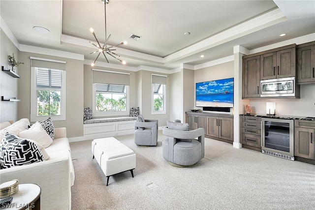 living room featuring beverage cooler, plenty of natural light, a raised ceiling, and a chandelier