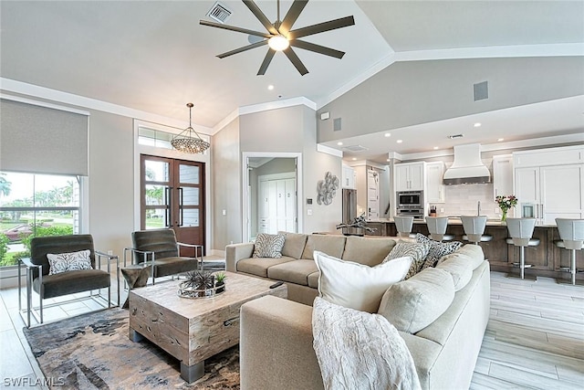 living room with vaulted ceiling, light hardwood / wood-style flooring, french doors, ceiling fan, and ornamental molding