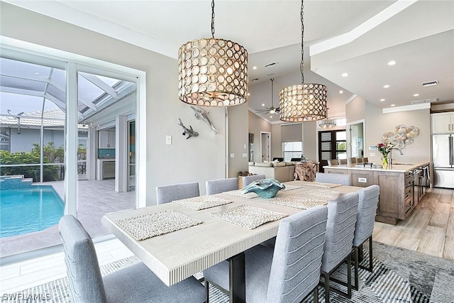 dining area featuring sink, vaulted ceiling, and light hardwood / wood-style flooring