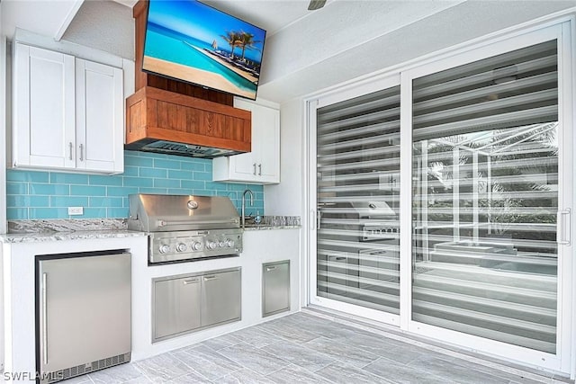 kitchen with stainless steel refrigerator, custom exhaust hood, backsplash, and white cabinetry