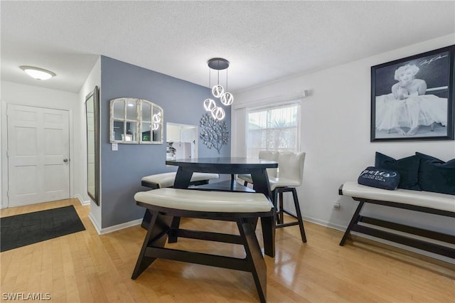 dining space with a textured ceiling and light hardwood / wood-style flooring