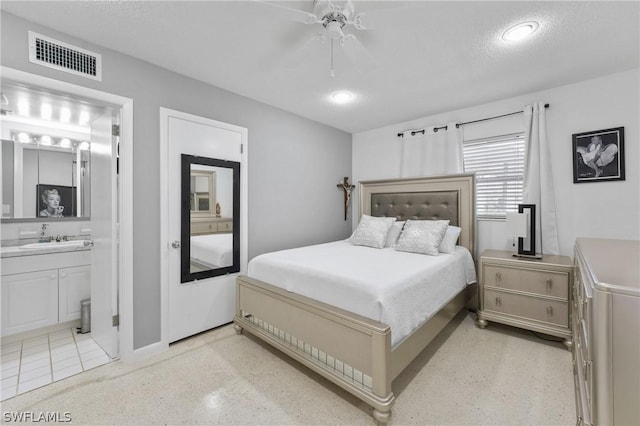 bedroom featuring a textured ceiling, ceiling fan, sink, and connected bathroom