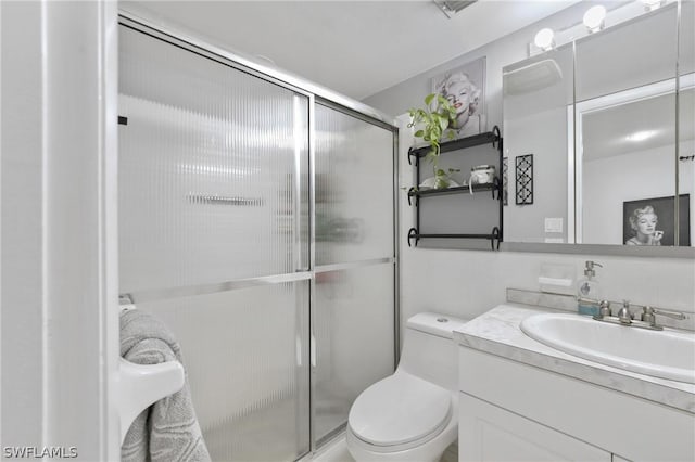 bathroom with vanity, toilet, and a shower with door