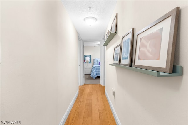 corridor featuring a textured ceiling and light wood-type flooring