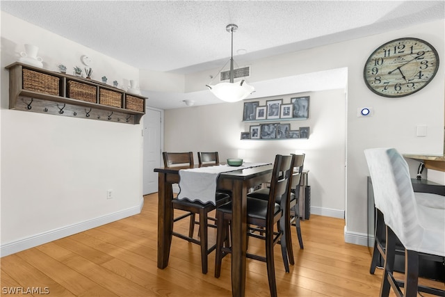 dining space with hardwood / wood-style flooring and a textured ceiling