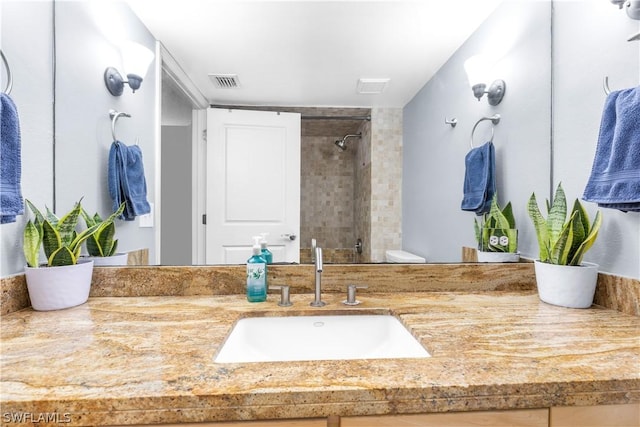 bathroom featuring vanity, a tile shower, and toilet