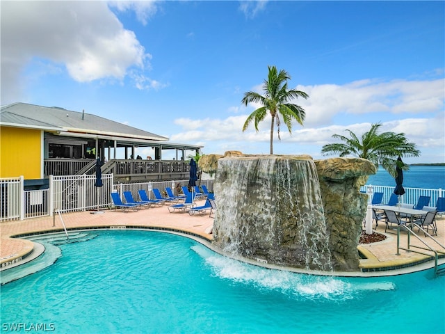 view of pool with pool water feature, a water view, and a patio