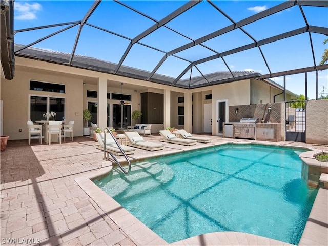 view of swimming pool with exterior kitchen, glass enclosure, ceiling fan, and a patio