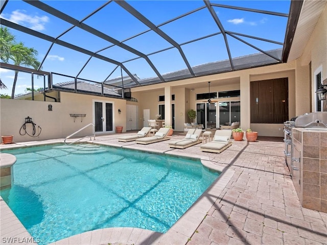 view of swimming pool with a lanai, an outdoor kitchen, french doors, and a patio area