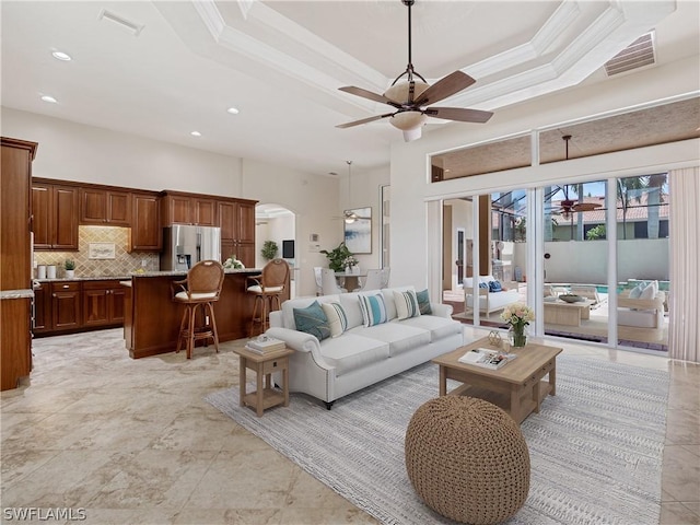 living room featuring ceiling fan, a tray ceiling, and ornamental molding