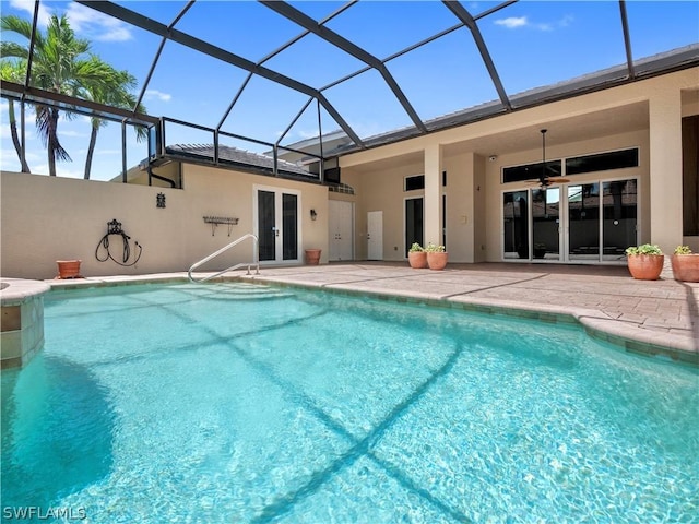 view of swimming pool featuring ceiling fan, glass enclosure, french doors, and a patio