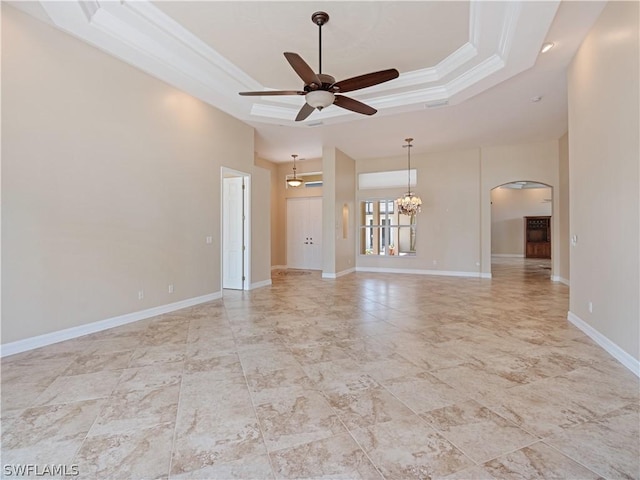 spare room featuring ceiling fan with notable chandelier, a tray ceiling, crown molding, and a towering ceiling