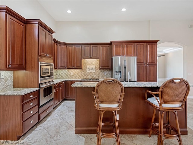 kitchen with light stone countertops, a kitchen breakfast bar, stainless steel appliances, and a center island