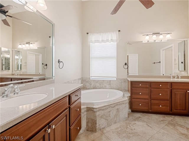 bathroom with ceiling fan, a relaxing tiled tub, and vanity