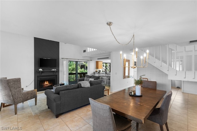 dining space featuring a fireplace, light tile patterned flooring, and an inviting chandelier