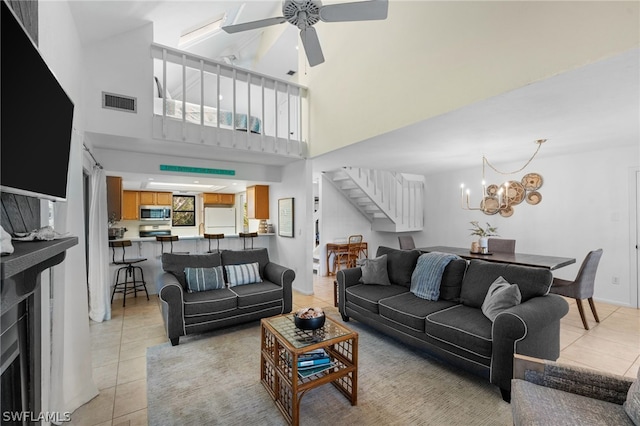 tiled living room featuring ceiling fan with notable chandelier and a towering ceiling