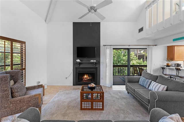 living room with ceiling fan, beam ceiling, high vaulted ceiling, a fireplace, and light tile patterned flooring