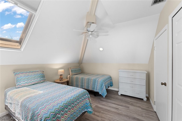 bedroom with a closet, ceiling fan, vaulted ceiling with skylight, and light hardwood / wood-style flooring