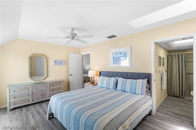 bedroom with wood-type flooring, ceiling fan, and vaulted ceiling with skylight