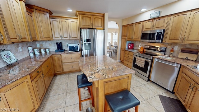 kitchen with tasteful backsplash, stainless steel appliances, a kitchen breakfast bar, and a center island