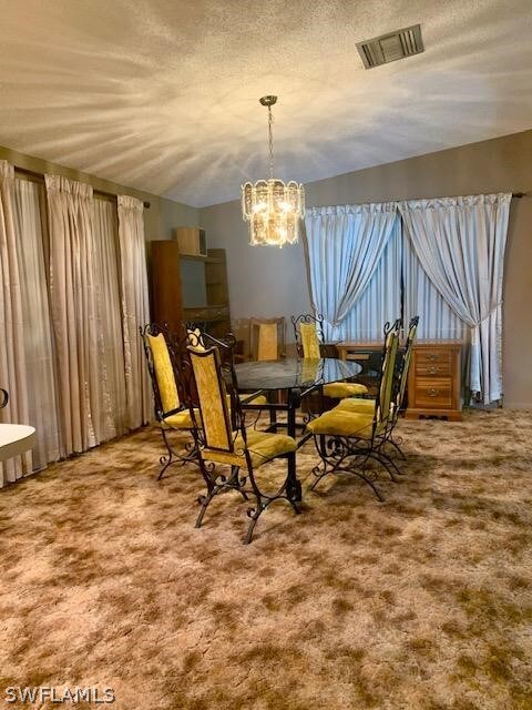 dining area featuring carpet, a notable chandelier, and a textured ceiling