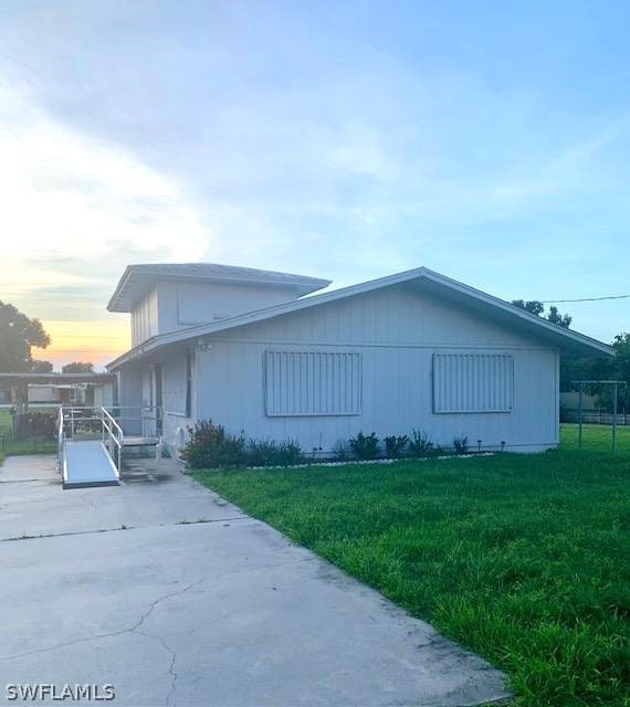 property exterior at dusk with a yard and a patio