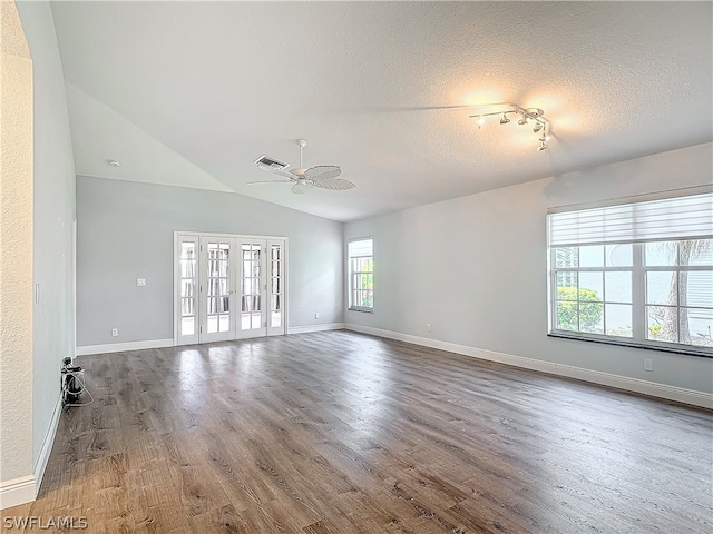 empty room featuring a textured ceiling, vaulted ceiling, wood-type flooring, french doors, and ceiling fan