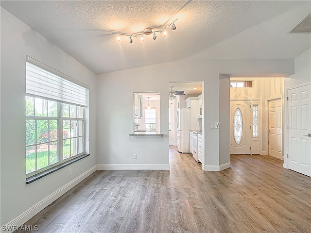 interior space with lofted ceiling, hardwood / wood-style flooring, and a textured ceiling