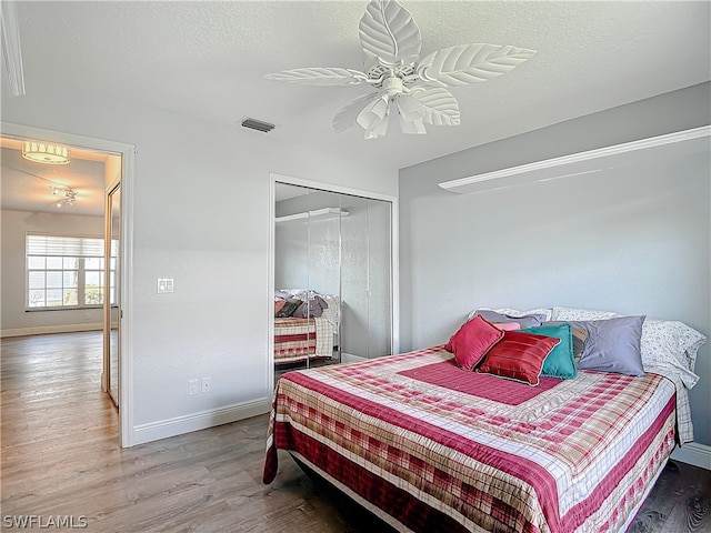 bedroom with hardwood / wood-style floors, ceiling fan, a closet, and a textured ceiling