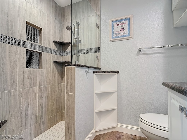 bathroom with vanity, toilet, hardwood / wood-style flooring, and tiled shower