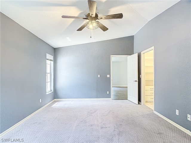 carpeted spare room featuring a textured ceiling, ceiling fan, and vaulted ceiling