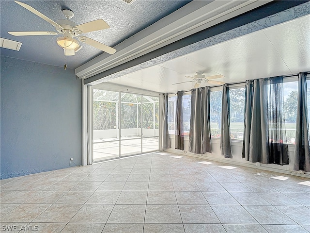 empty room featuring a wealth of natural light, ceiling fan, and a textured ceiling