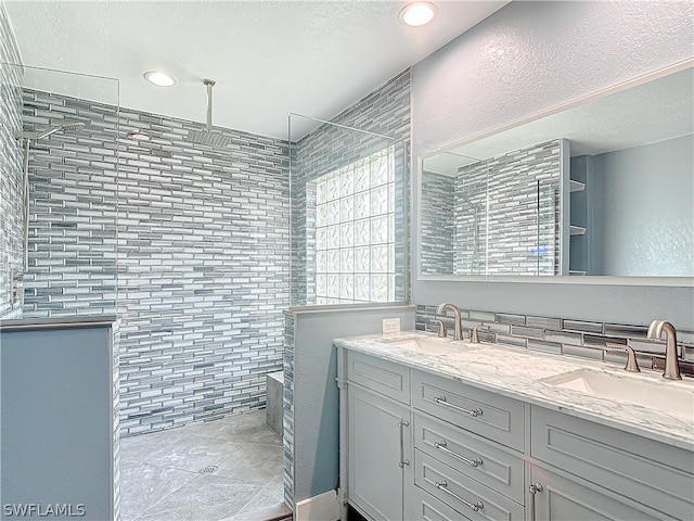 bathroom with vanity, a textured ceiling, and tiled shower