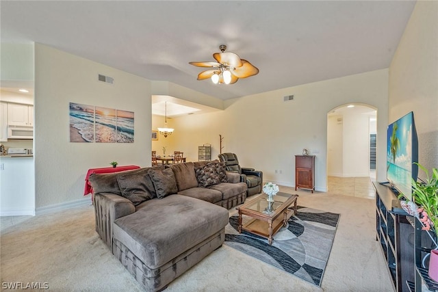 carpeted living room featuring ceiling fan with notable chandelier