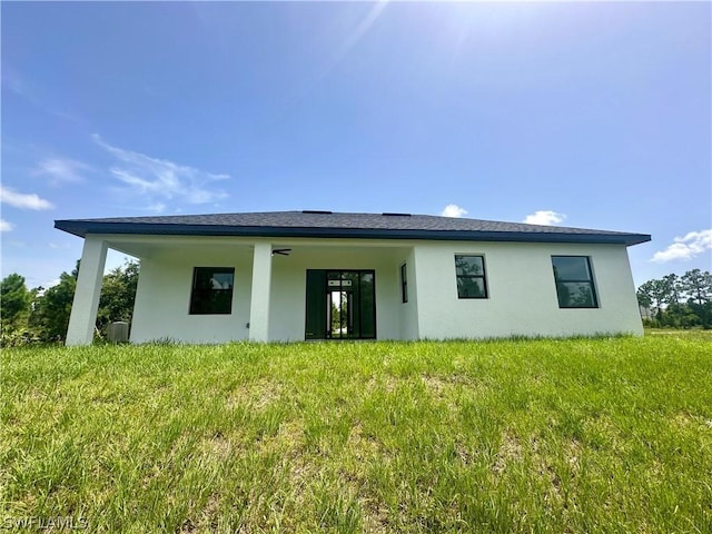 rear view of property with a lawn and ceiling fan