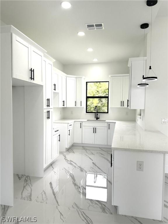 kitchen featuring sink, white cabinets, hanging light fixtures, kitchen peninsula, and light stone countertops