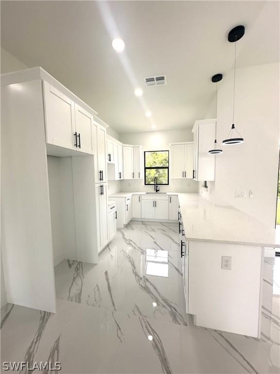 kitchen with kitchen peninsula, sink, hanging light fixtures, and white cabinets