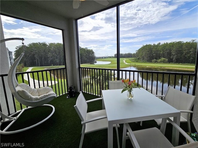 sunroom / solarium with ceiling fan and a water view