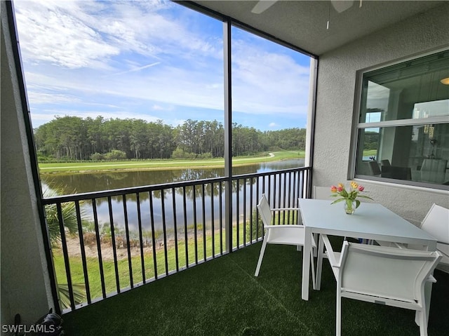 sunroom / solarium with ceiling fan and a water view