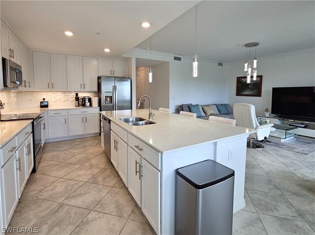 kitchen with stainless steel appliances, an island with sink, hanging light fixtures, sink, and white cabinetry