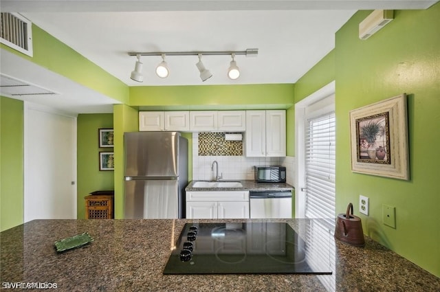 kitchen featuring black appliances, tasteful backsplash, white cabinets, and a sink