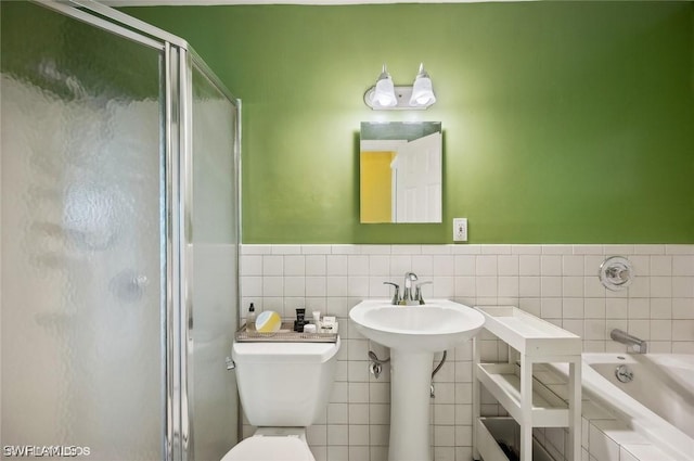 full bathroom with tiled bath, toilet, a wainscoted wall, tile walls, and a stall shower