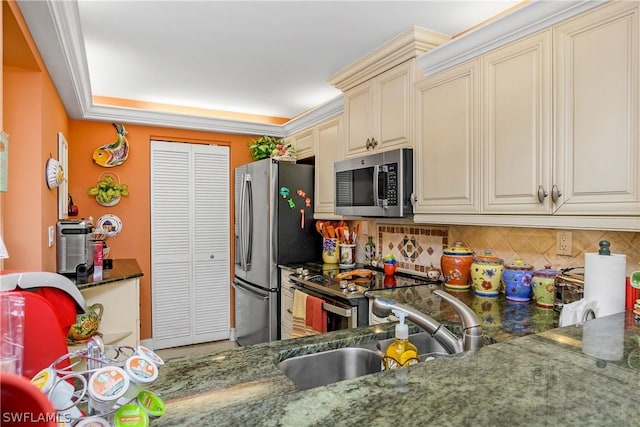 kitchen with tasteful backsplash, dark stone counters, cream cabinetry, sink, and stainless steel appliances