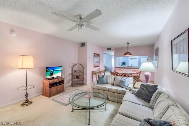 living room with ceiling fan, light colored carpet, and a textured ceiling